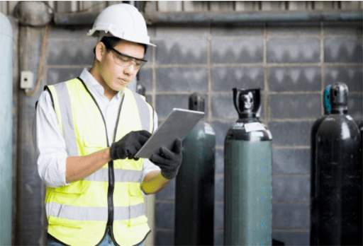 A Male heavy industrial worker using a digital tablet inside manufacturing